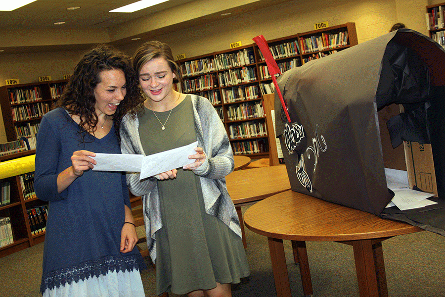 Seniors Kalyn Mizelle and Kaylee Palumbo laugh together while looking at the letters they wrote to themselves as freshman.