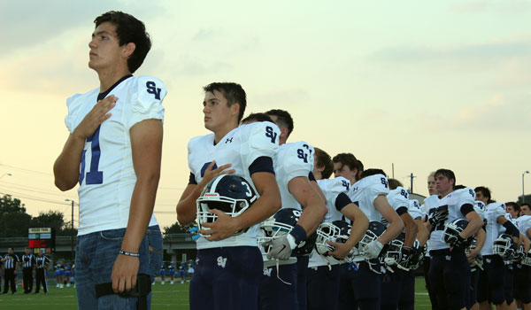Football players stand for the national anthem for Friday's victory over Austin Anderson.