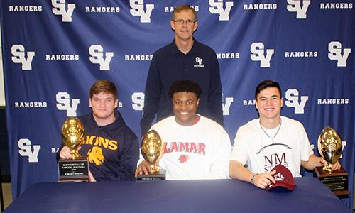 Coach Larry Hill stands behind Kolt Fullen, Brandon Arnold and Josh Adkins after they sign their letters of commitment to play football.