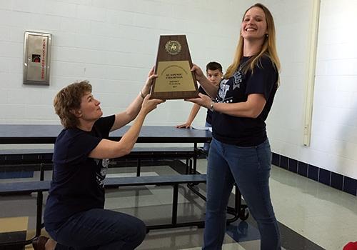 Former UIL coordinator Denise Nipper and current UIL coordinator L. Sellers hold up the first place academic team plaque while sophomore Niles Nelson watches in the background.  