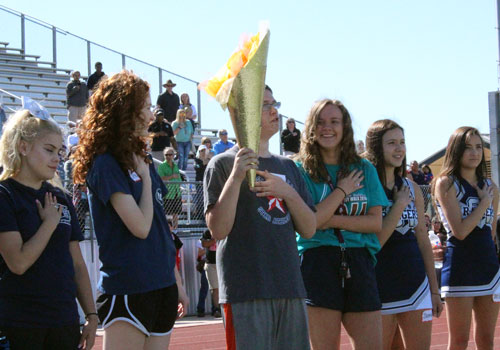 STAR athlete and torchbearer Zach Allen sings along to national anthem with cheerleaders and FACS volunteers on both sides.