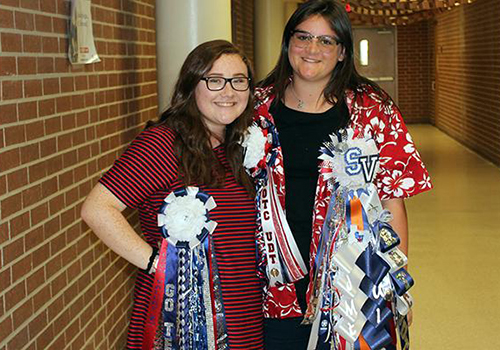 Sophomores Lyndsey Reyes and Jaymie Nickles smile with mums galore in C wing.