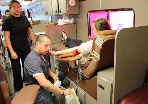 ROLLING UP SLEEVES  Medical personel gathers donated blood from senior Hallie Reeves in the first blood drive bus parked at the main entrance. Student volunteers were excused from class to donate. 