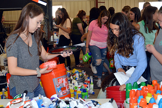 Cleaning Up Junior Hanna Anderson and freshman Summer Williams use the lists to fit brushes and mosquito repellent into the orange buckets. Supplies came from students around the school and had to be sorted and placed in the right bucket.

