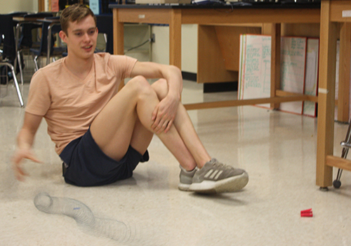 Junior Konnar Klinksiek oscillates the helical spring Feb. 28 in his physics class to see how waves interact.