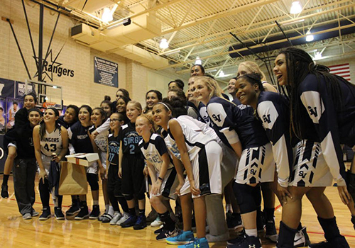 The varsity girls basketball team poses with junior athletes during half time. They defeated East Central 50 - 32.