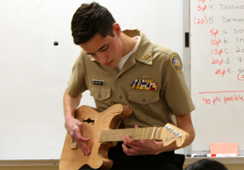 Junior John Mamalakis plays his homemade guitar in class for the physics instrument project on April 11.