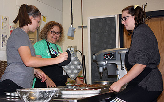 New culinary teacher, Chef Marucci checks in on students working on a dessert project. 