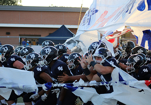 The football team roars onto the field before the season opener against Midland Lee on Aug. 31