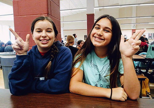Freshmen Anna Vig and Aleena Fusse hold up two different Ranger symbols in the cafeteria on Sept. 21.