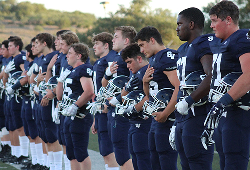 The football team stands for the national anthem before the first home game on Aug. 30.