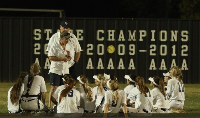 Coaches Wayne and Lisa Daigle talk with the team in the outfield.