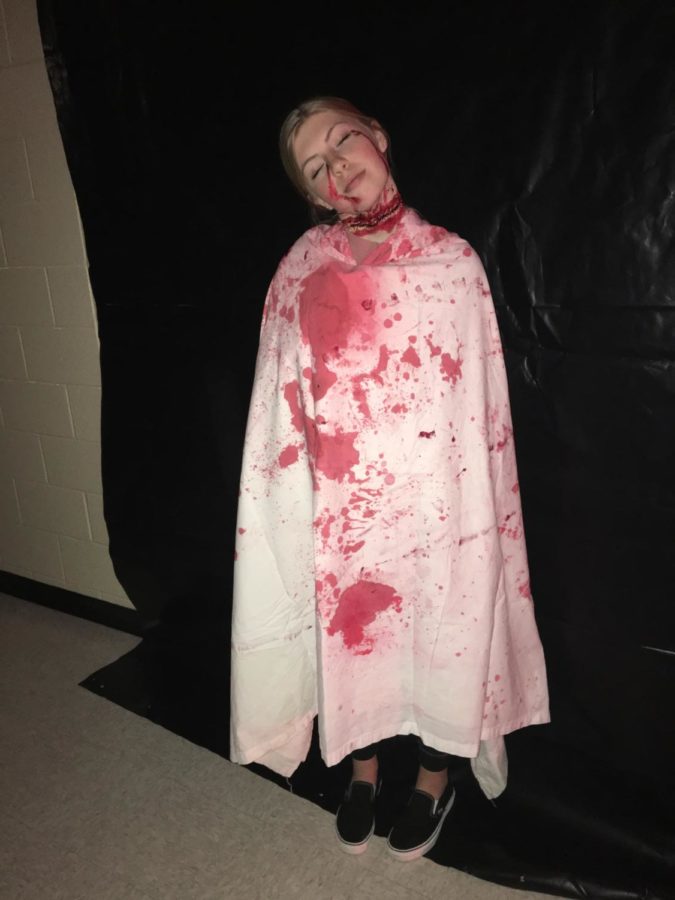 With "bloody" makeup and clothes, junior Madison Wilhelm prepares to scare in the slaughterhouse section of the haunted house.
