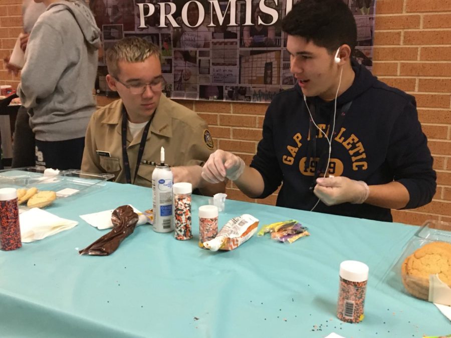 Junior Sebastian Mangual and freshman Jackson Moshier man the cookie decorating booth for ROTC in the main hallway.