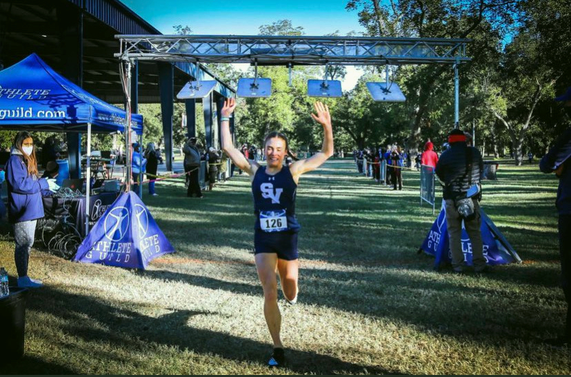 Senior Amalie Mills, ecstatic after running a personal best, qualifies for the regional meet with a first place finish at district.