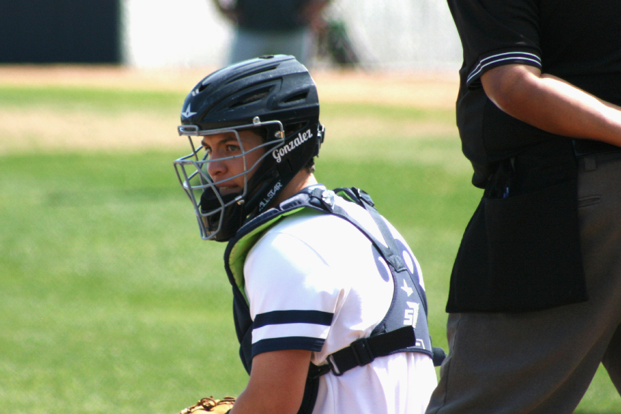 Looking for a signal, Ethan Gonzalez crouches behind home plate. Gonzalez, a sophomore, hit a walk-off single in extra innings on Saturday to take down No. 1 Reagan.