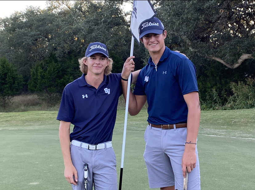 Two of the golf players stand next to the flag on hole 18.