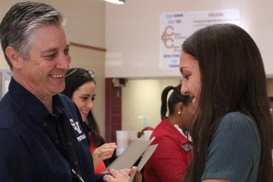Principal Michael Wahl gives a National Merit Scholar certificate to Jaci Mesa during the breakfast ceremony Oct. 29 in the cafeteria.