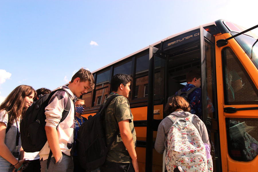 After school early in the academic year, riders load up behind the band hall. A shortage of drivers leads the district to temporarily cancel some routes when a driver is unavailable.