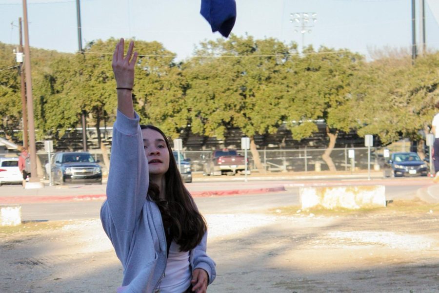 Junior member tosses her bean bag in hopes of making a cornhole.