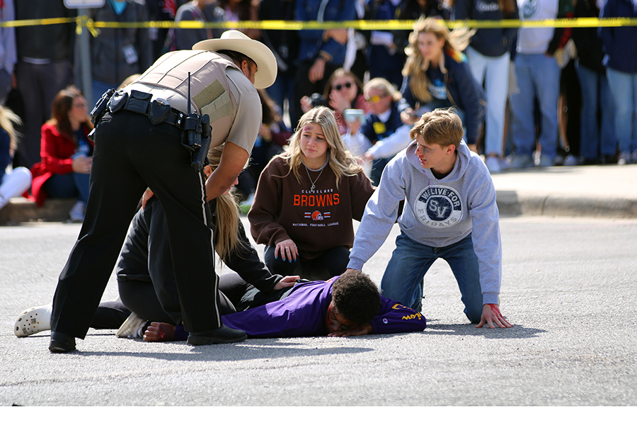 A crowd gathers around Malachi Lane, who was "killed" in a drunk driving accident.