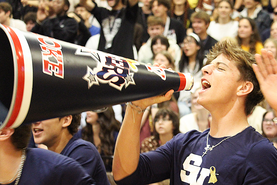 Varsity football player Weston Ross chants with a cheerleader's megaphone.
