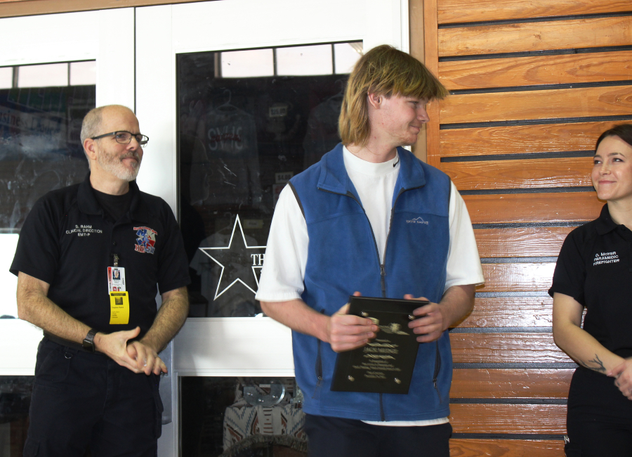 After receiving a plaque Wednesday from Stephan Rahm, clinical director for Bulverde Spring Branch Fire & EMS, senior Jack Mudge gets congratulations from EMT/paramedic D. Moyer. Moyer was among the emergency medical personnel who responded to the call for a heart attack where Mudge performed CPR and saved a man's life.