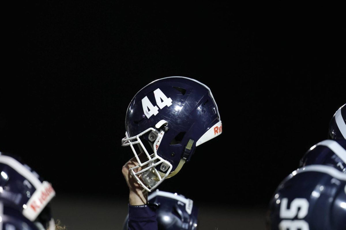 After football's 54-17 win against Seguin, then junior Davis Kuhn holds his helmet up for the playing of the school's alma mater.