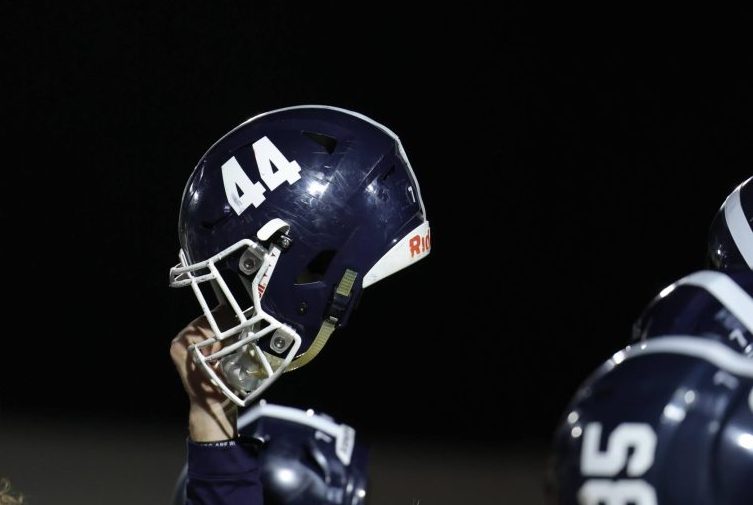 After football's 54-17 win against Seguin, then junior Davis Kuhn holds his helmet up for the playing of the school's alma mater.