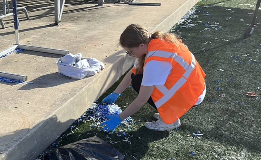 On the Saturday after homecoming, National Honor Society member Isabella White grabs handfuls of pom pom debris from the previous night's football game.