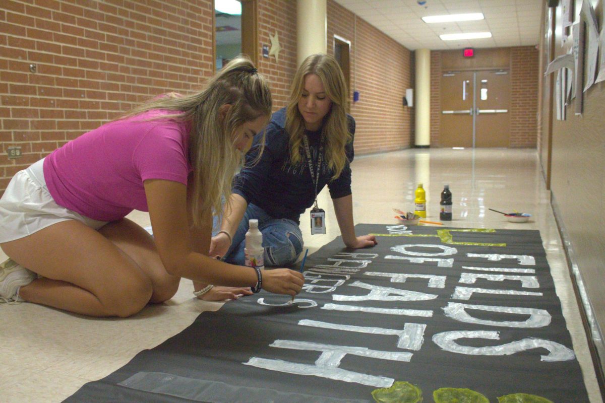 Senior Ximena Ortega and FACS teacher Aubrie Herring paint a poster to advertise for Wednesdays Fields of Faith.