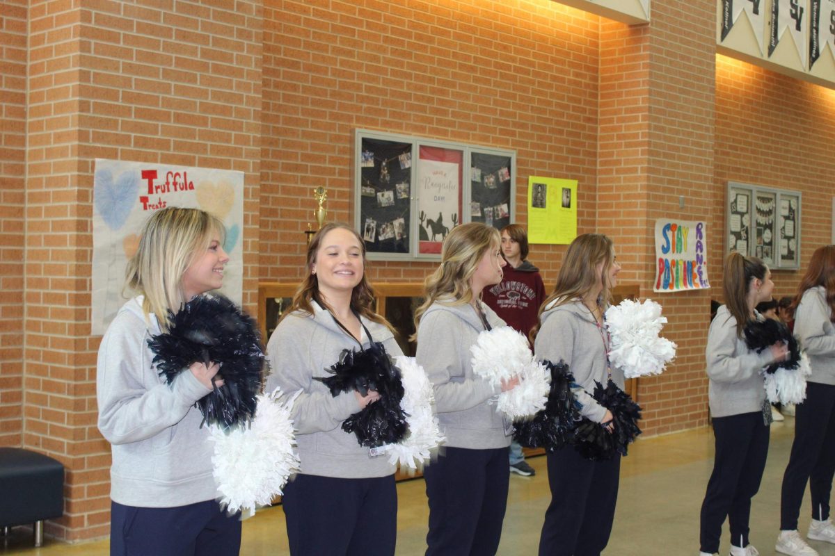 Junior varsity cheerleaders line the walkway to cheer on the state bound wrestling team.