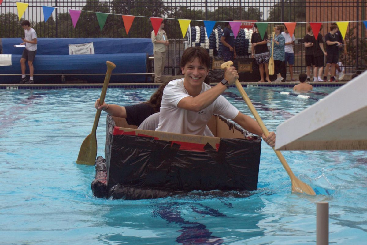 Junior Aidan Kellner laughs as he rows his group's boat to the end of the pool. Kellner was in a group with juniors Marlowe Berry and Amber Smith.