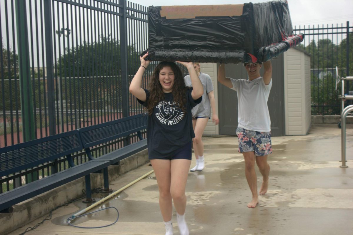 Junior Marlowe Berry carries her boat to the dumpster after successfully making it across the pool. Berry's group added cylindrical cardboard on the sides for extra support.