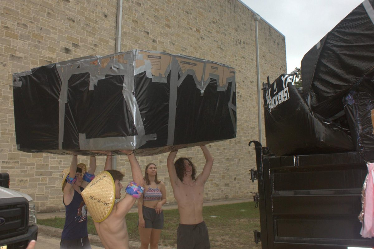 Juniors Braeden Wills, Zach Niles and Jameson Maldonado attempt to places their boat in the dumpster after completing their boat race. 