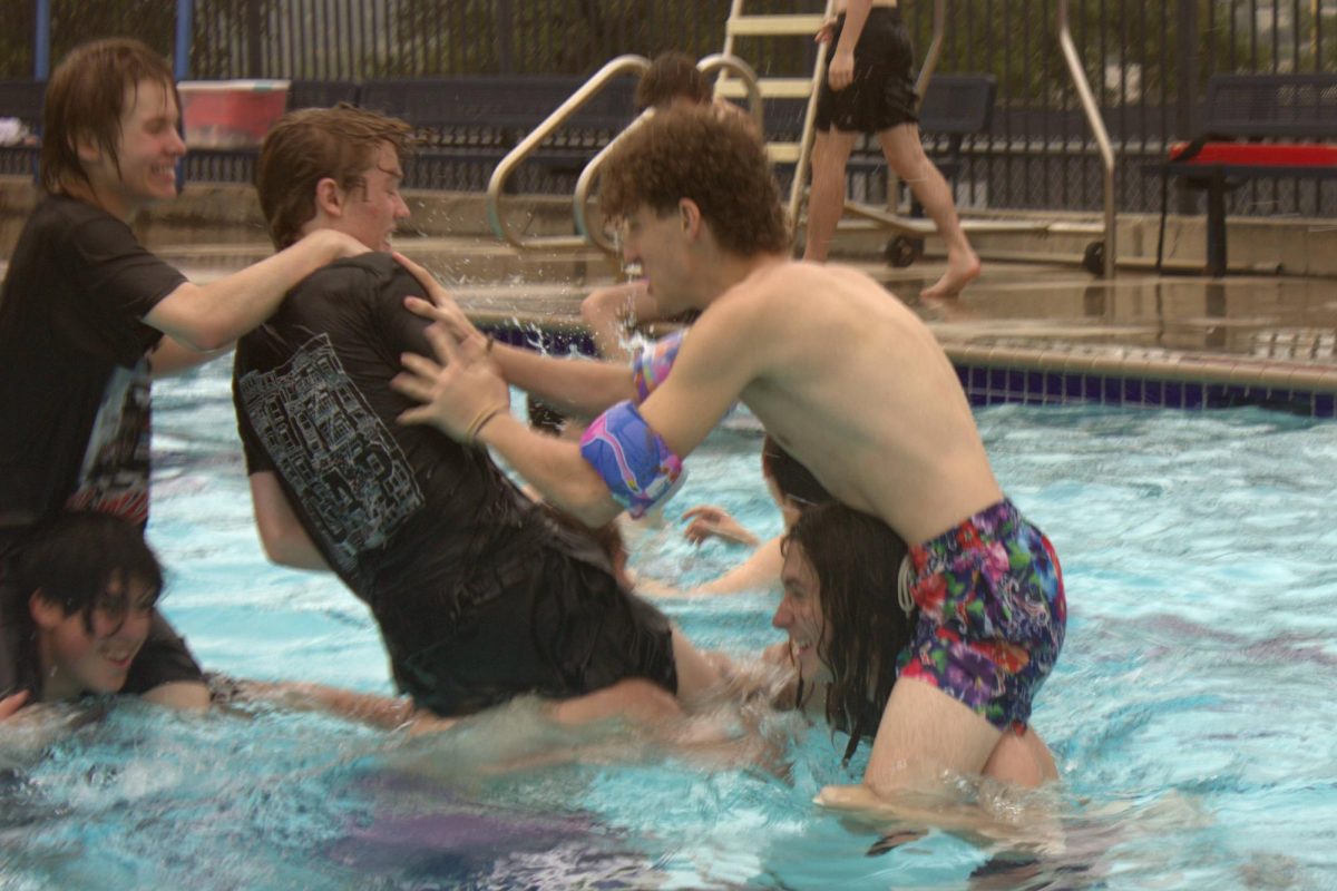Junior Braeden Wills shoves a student off another student's shoulders in a game of chicken fight. After all the boat races were finished, students did not hesitate to jump in the pool.